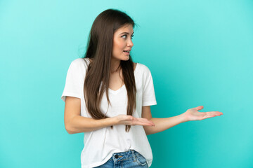 Young caucasian woman isolated on blue background with surprise expression while looking side