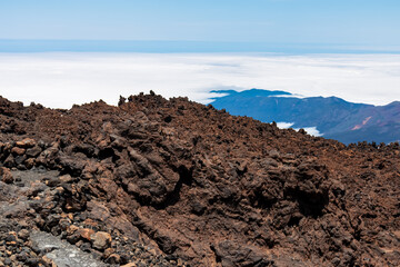 Scenic view from summit of volcano Pico del Teide over the island of Tenerife, Canary Islands, Spain, Europe. Vista on barren landscape, solidified lava, ash, pumice. Valley and sea covered in clouds