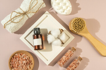 Fototapeta na wymiar A pink sea salt in mini glass bottles, a white anticellulite body soap, a natural brush and a face serum or essential oil are ready for the spa procedures in the salon
