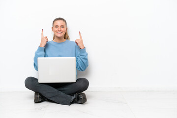Young woman with a laptop sitting on the floor pointing up a great idea