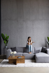 Happy young woman talking phone in loft apartment