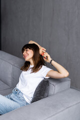 Serene young woman pretty relaxing on couch in living room. Calm woman freelancer crossing hands behind head, closing eyes and taking a break during remote work day at home, stress free concept.