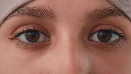 Close-up of the arabian female black eyes of muslim woman. Islamic girl gaze looking at camera. Arabian lady in hijab with dark eyeliner long lashes make-up look mystery