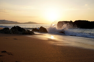 Evening over the ocean. Clouds and sky in anticipation of the sunset over the horizon Horizontal shot. Rocks and surf.. Poyazh. Splashes of water in the bright light of the sun
