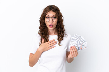 Young woman with curly hair taking a lot of money isolated background on white background surprised and shocked while looking right