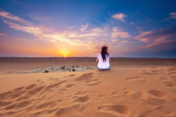 Frau beobachtet den Sonnenuntergang über der Wüste im Oman