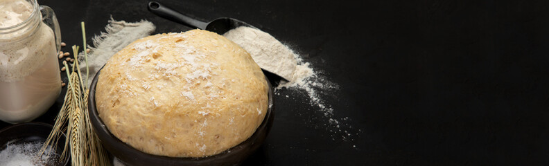 Raw dough pastry in a bowl on dark background.