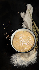 Raw dough pastry in a bowl on dark background.