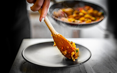 woman puts food from a frying pan into a plate