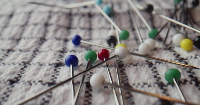 Many Needles and pins with colored heads scattered on the fabric. Extreme macro
