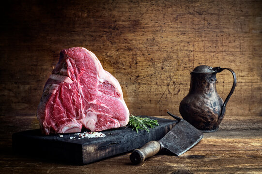 Traditional raw porterhouse angus beaf steak with spice and herbs offered as close-up on a rustic charred wooden board with copy space
