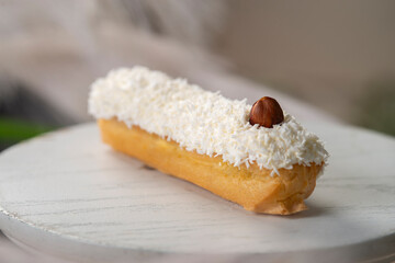 french eclair with coconut crumble hazelnut on a white desk