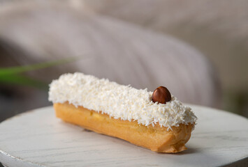 french eclair with coconut crumble hazelnut on a white desk