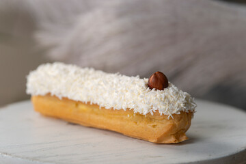 french eclair with coconut crumble hazelnut on a white desk