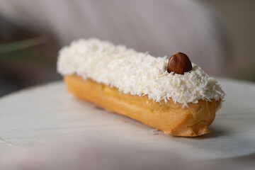 french eclair with coconut crumble hazelnut on a white desk
