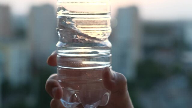 Man shaking water in a plastic bottle, close-up