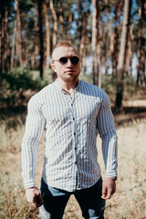 Photo of cheerful man look empty space wear sunglass outdoor. Holiday in forest