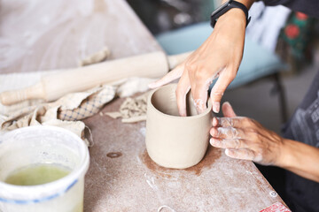 Female ceramist working in pottery studio. Ceramist's Hands Dirty Of Clay. Process of creating pottery. Master ceramist works in her studio