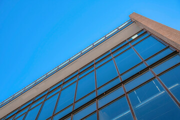 Modern commercial building lined with glass windows against clear blue sky