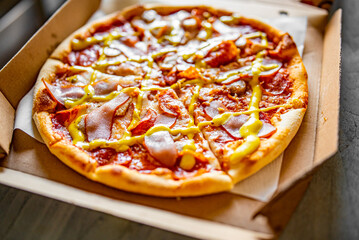Pizza with Mozzarella cheese, ham, tomato sauce, pepper, pepperoni, sausage and mustard sauce. Italian pizza in box