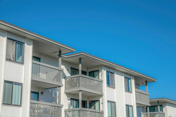 Fototapeta na wymiar Homes with balconies and white walls against blue sky in Del Mar California