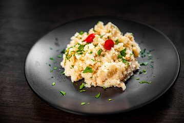 Risotto in a black plate on wooden background