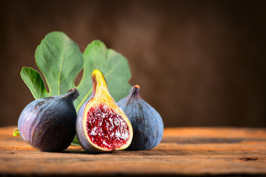 Fig fruit close up. Ripe fig fruits with leaf close-up. Beautiful sweet fresh organic figs on a wooden table. Label design. Healthy vegan food. 