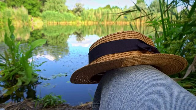 Women's straw hat on the background of the lake in summer. Plants on the lake. Blue lake with plants. Overgrown river with water lilies. Calm water in a small lake.