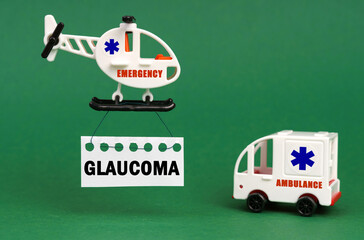 On a green surface, an ambulance car and a helicopter with a sign - GLAUCOMA
