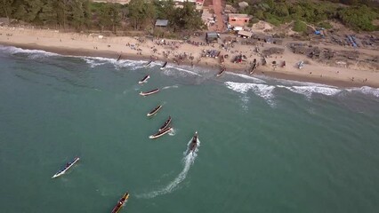Aerial footage of beach with people and traditional senegalese fishing boats