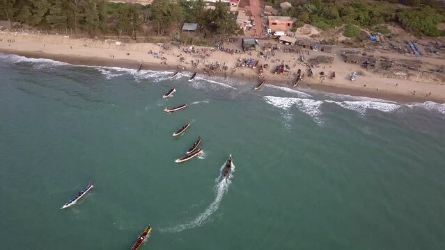 Aerial footage of beach with people and traditional senegalese fishing boats