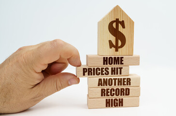 On wooden blocks with the inscription - Home prices hit another record high, there is a model of the house.