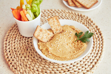 Homemade hummus with olive oil, cookies, parsley and fresh vegetables on the table. Healthy vegetarian rustic snacks close up.