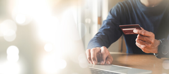 Man hand holding credit card and using laptop at home, Businessman or entrepreneur working, Online shopping, e-commerce, internet banking, spending money concept.