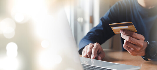 Man hand holding credit card and using laptop at home, Businessman or entrepreneur working, Online shopping, e-commerce, internet banking, spending money concept.
