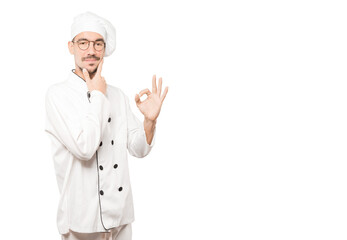 Worried young chef doubting and making a gesture of approval