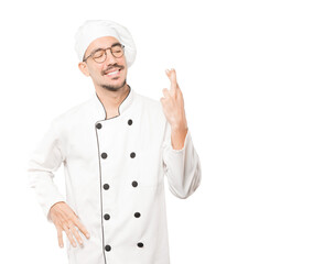 Happy young chef doing a crossed fingers gesture