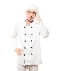 Depressed young chef posing against background