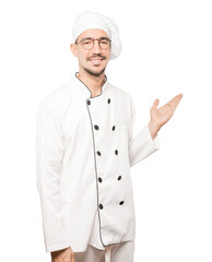 Friendly young chef making a gesture of welcome