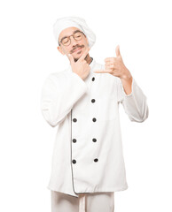 Hesitant young chef making a gesture of calling with the hand