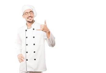 Happy young chef making a gesture of calling with the hand