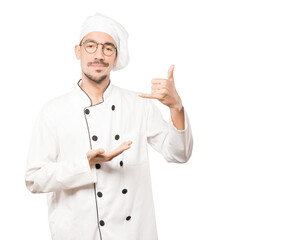 Hesitant young chef making a gesture of calling with the hand