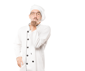 Friendly young chef making a gesture of sending a kiss with his hand