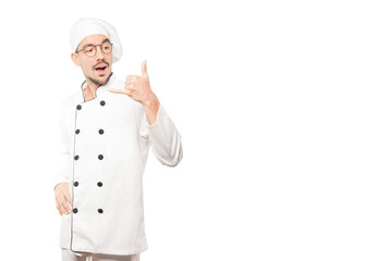Amazed young chef making a gesture of calling with the hand