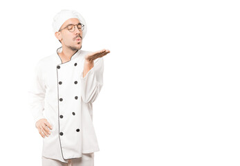 Friendly young chef making a gesture of sending a kiss with his hand