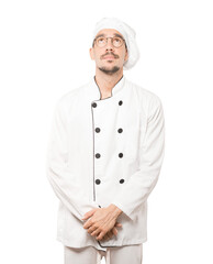 Serious young chef looking against background