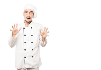 Scared young chef screaming against background