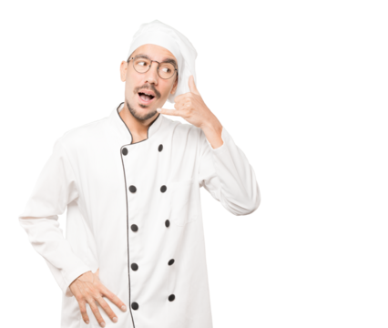 Amazed young chef making a gesture of calling with the hand