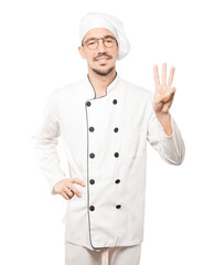 Young chef making a number three gesture