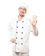 Young chef making a number four gesture